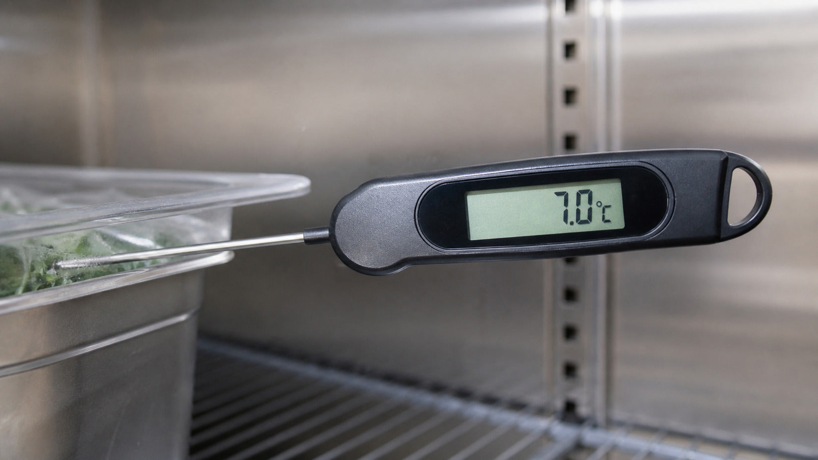 Illustrative close-up of a digital probe thermometer reading 7.0°C in a restaurant cooler